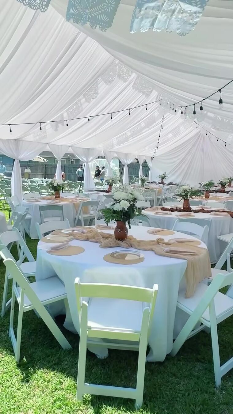 Round tables with flowers under a white draped tent
