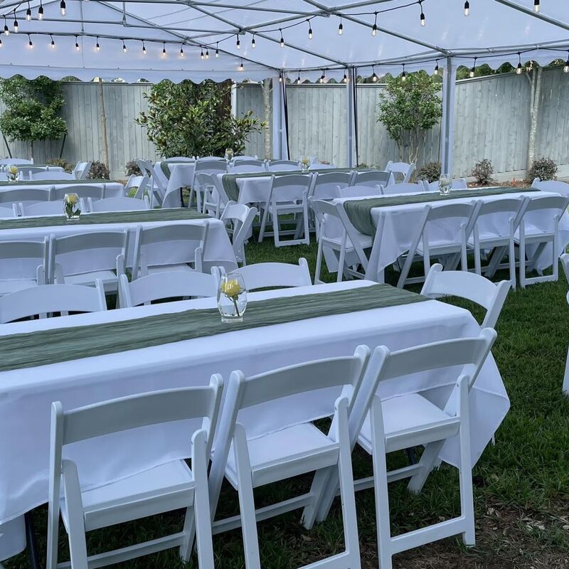 Long tables with green runners and white chairs under a tent