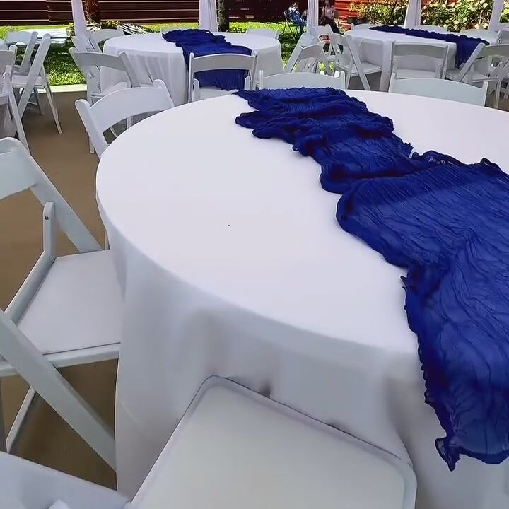 Round table with a navy runner under a white draped tent