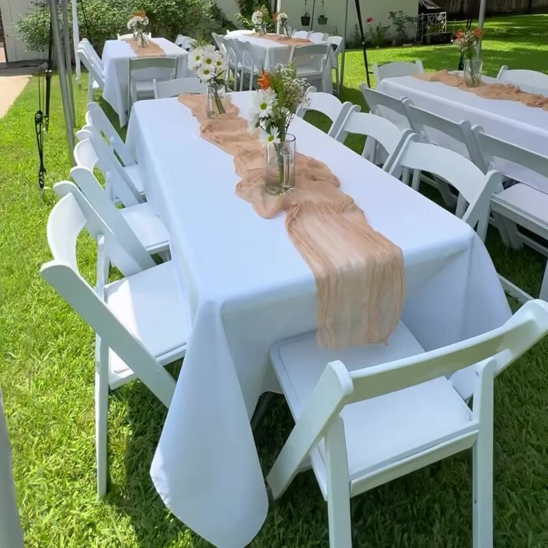 Rectangle tables with peach runners and white chairs on a lawn