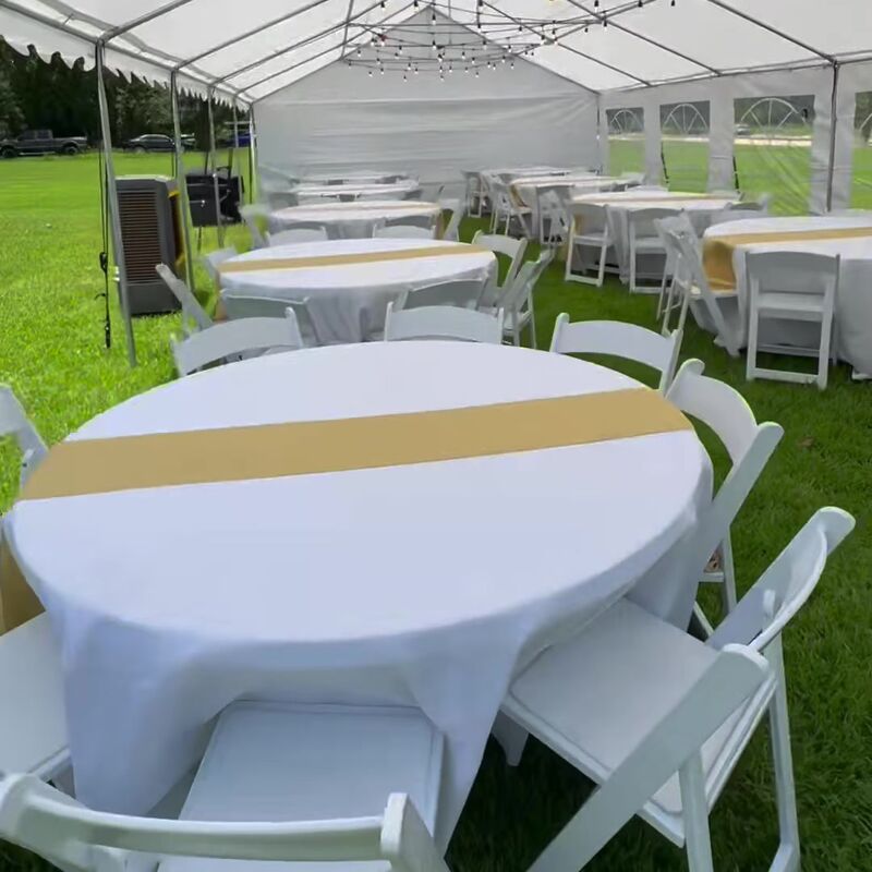Round table with a gold runner and white chairs under a tent