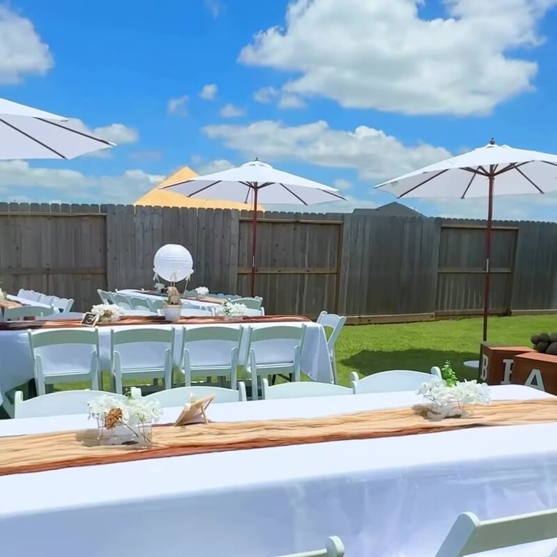 White umbrellas over long tables in a backyard